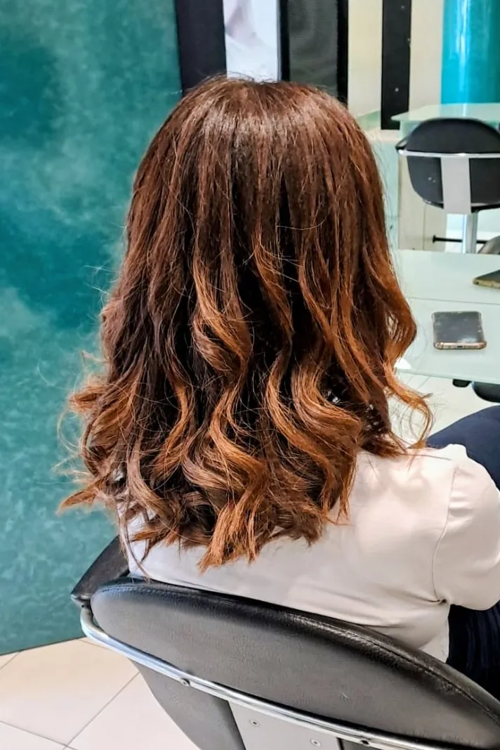 Taglio con onde morbide e riflessi ramati, vista di spalle, salone Nuova Immagine Coiffeur a Milano Brenta - Corvetto
