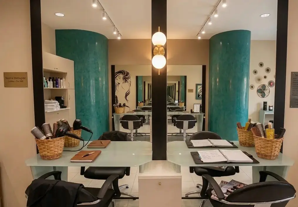 Due postazioni affiancate del salone Nuova Immagine Coiffeur a Milano Brenta e Corvetto, con specchi, colonne color petrolio e cestini di spazzole